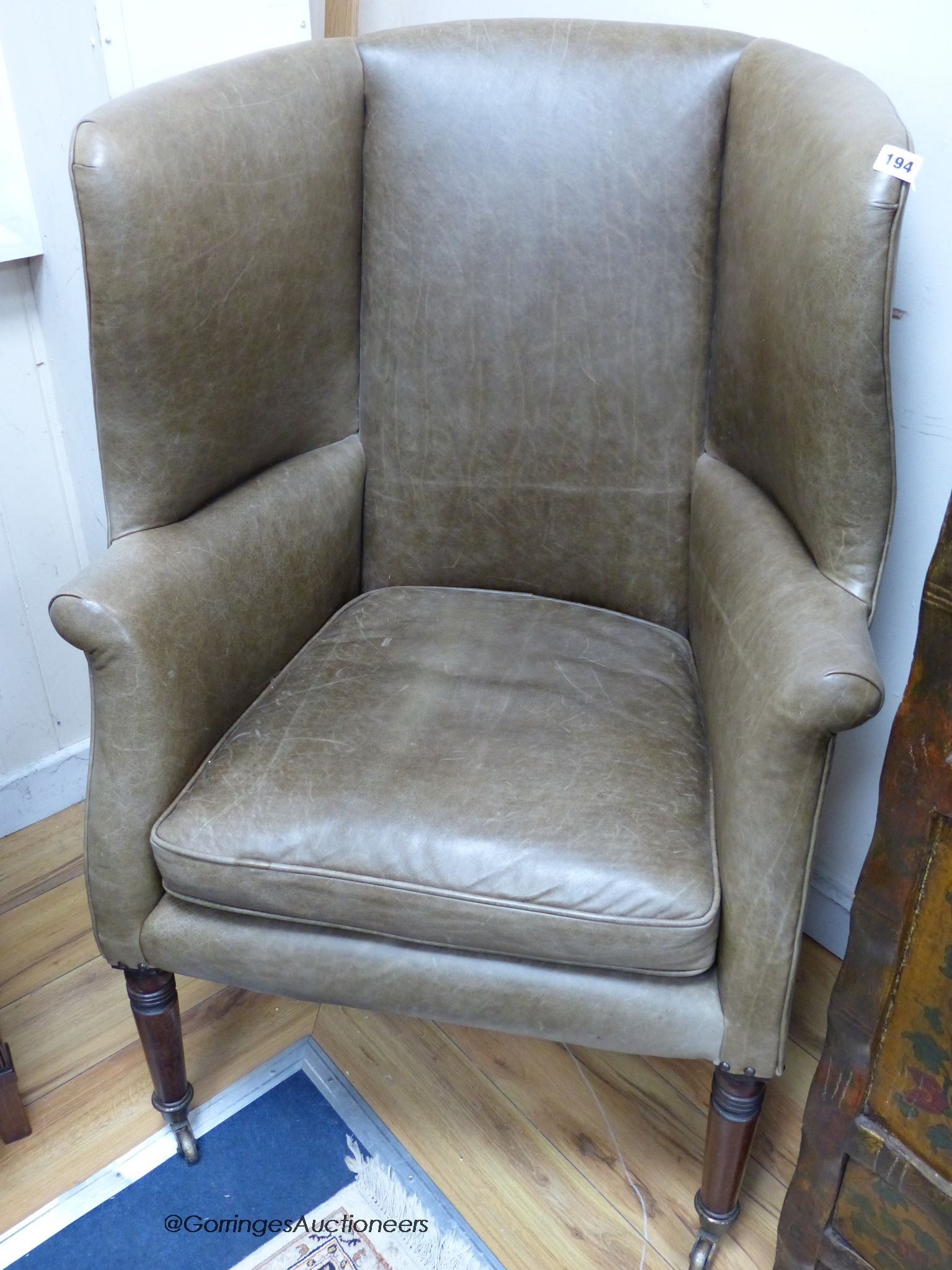 A Regency barrel back wing armchair upholstered in pale green leather